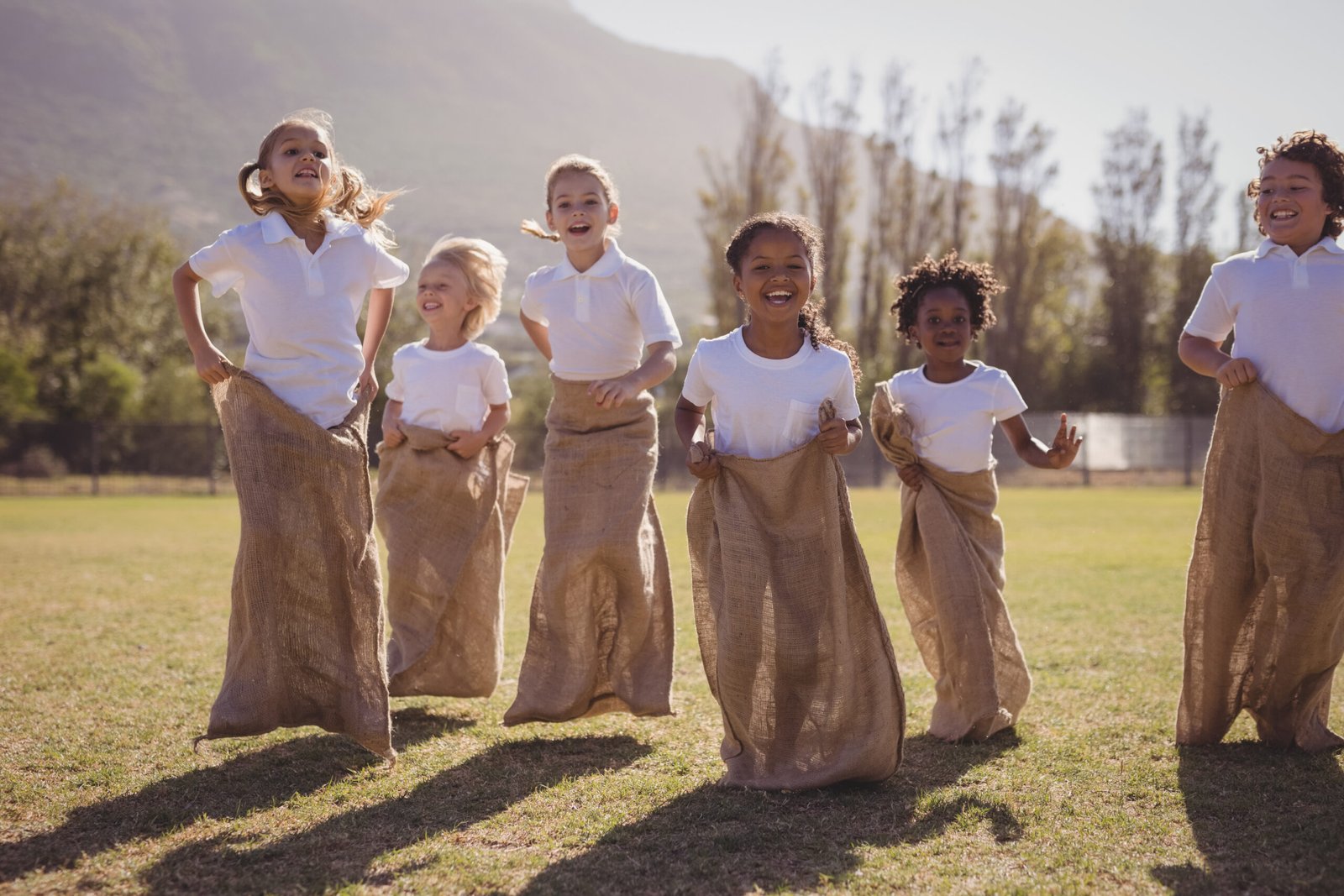 Portrait of happy schoolgirls standing in sack during race on a sunny day